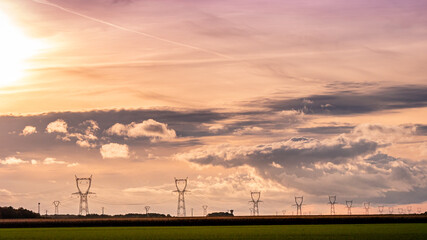 Alignement de pylônes électriques sous un magnifique coucher de soleil