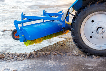 Cleaning and sweeping streets from snow. Tractor with new hinged brush clears area. Close-up.
