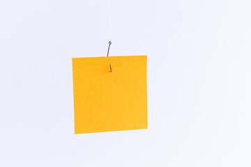 Mockup of a Blank Orange Memo Paper with Copy Space Hanging on a Fishing Hook Against the White Background. Reminder or To Do List. Sticky Note Template
