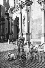 Stylish woman wearing polka dot suit posing with different dogs