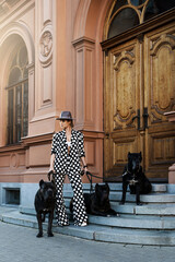 Stylish woman wearing polka dot suit posing with the Cane Corso dogs