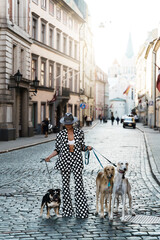 Stylish woman wearing polka dot suit posing with different dogs