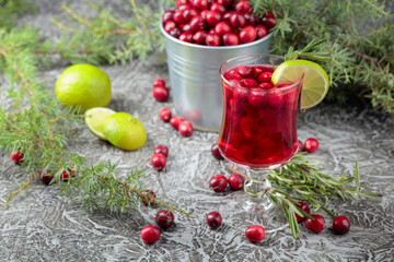 Glass of cranberry drink with berries, lime, and rosemary.