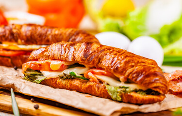 Croissants with bacon, cheese and vegetables on wooden board. Close up