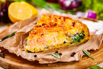 Pie with salmon, potato and spinach on wooden cutting board