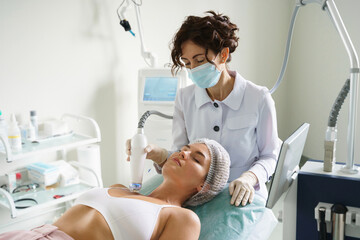 Doctor and woman client during radiofrequency lifting treatment in a medical aesthetic clinic