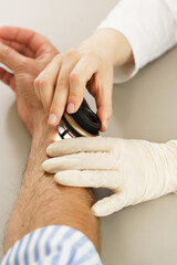 Dermatologist is using dermatoscope for skin examination.