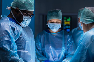 Multiracial team of professional medical surgeons performs the surgical operation in a modern...