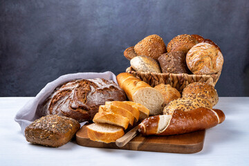 Delicious freshly baked buns and bread on a white table and rustic background. Front view, copy space