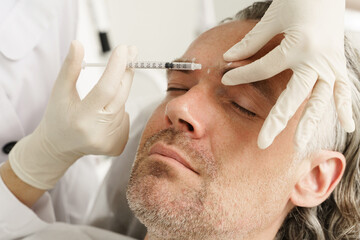 Middle aged male client during filler injections in a clinic