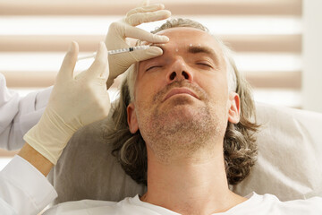 Middle aged male client during filler injections in a clinic