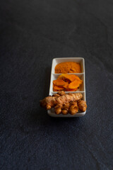 turmeric in three presentations root laminated and powder on a black background