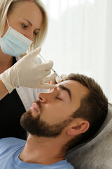 Female doctor and male client during filler injections