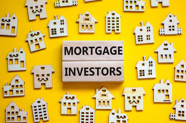 Mortgage investors symbol. Concept words 'Mortgage investors' on wooden blocks near miniature wooden houses. Beautiful yellow background. Business, mortgage investors concept.