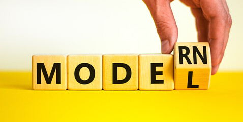 Modern model symbol. Businessman turns a wooden cube and changes the word model to modern. Beautiful yellow table, white background, copy space. Business and modern model concept.