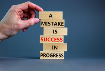 Mistake or success symbol. Wooden blocks with words A mistake is success in progress. Beautiful grey background, copy space. Businessman hand. Business, mistake or success concept.