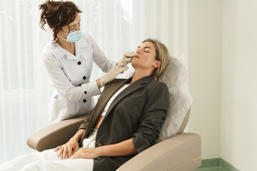 Doctor and client during lip augmentation filler injections in aesthetic medical clinic