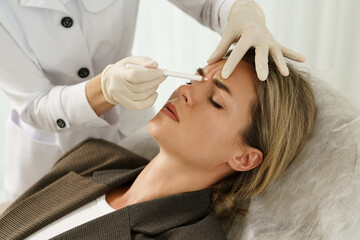Doctor making marks on client's face before filler injection