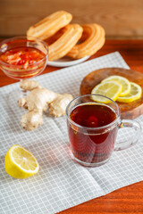 A cup of strong infused tea on a napkin next to lemon ginger.