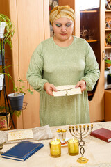 Jewish woman in traditional turban blesses matzo on Shabbat.