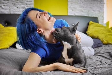 Woman and her french bulldog laying on a bed