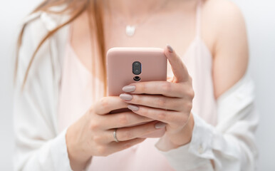 Female hands young woman using pink case smart phone social media, checking news, playing mobile games or texting messages close-up