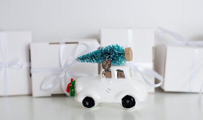 A small gifts and christmas ball car with a white ribbon on white background. Many white gifts with a bow. Christmas gifts. Gift for woman. Panorama christmas car with tree