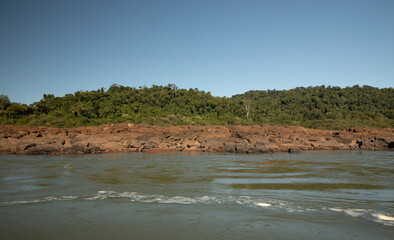 Wilderness. View of the river flowing across the green tropical jungle. The lush vegetation and rocky shore. 
