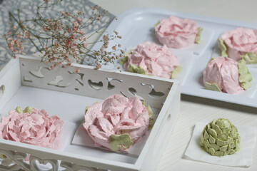 Marshmallow flowers. Are laid out on trays. Pink flowers and green marshmallow petals are visible. Close-up shot.