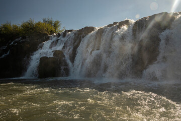 Sailing the river. The majestic Mocona waterfalls seen from the boat. The falling white water, rocks and river flowing across the jungle.