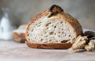 Loaf of freshly baked sourdough bread on cutting board with milk. Artisan rustic sourdough bread.