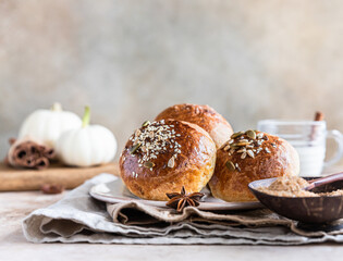 Fresh homemade pumpkin buns with brown sugar or seeds, light concrete background. Autumn bakery.