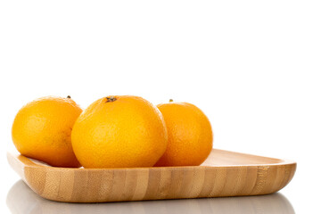 Several ripe organic tangerines in a plate made of wood, close-up, isolated on white.