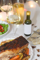 Pork belly roast, roasted vegetable, salad and wine on the festive table. Selective focus.