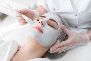 Face peeling mask, spa beauty treatment, skincare. Woman getting facial care by beautician at spa salon