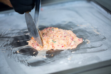 Stir-fried ice cream rolls at freeze pan. Rolled ice cream, hand made ice cream dessert. Fried ice cream machine with steel chilled pan.
