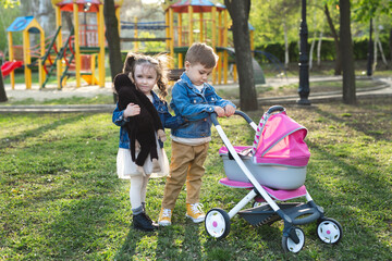 Little boy and little girl baby walk with a stroller for dolls.