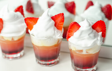 Colorful layered shots of drinks based on vodka, grenadine and orange juice decorated with whipped...