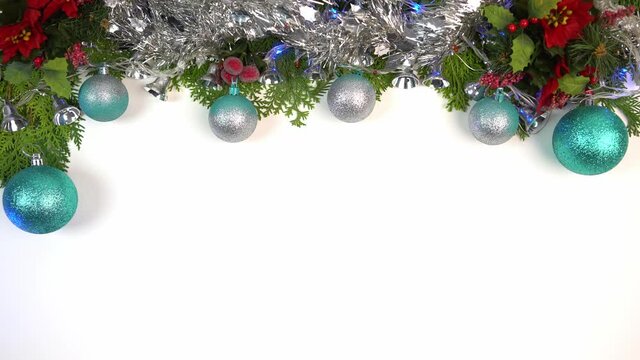 Frame green pine branch with Christmas balls, shiny tinsel, lights and serpentine on white background and space for text. Top view of fir tree branches and Xmas decoration banner and New Year concept