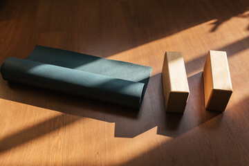 Closeup of two wooden yoga blocks and blue yoga mat on the wooden floor. - obrazy, fototapety, plakaty