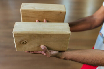 Close-up of a young man's hand holding wooden blocks for yoga and fitness.