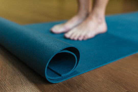 A girl stands on a blue yoga mat close-up. © Oleh