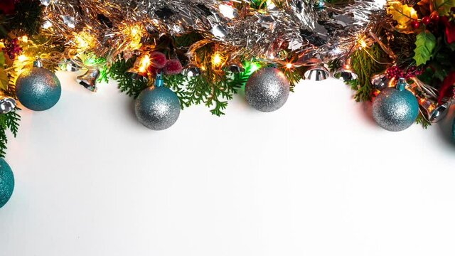 Festive christmas balls, shiny tinsel, lights and serpentine at border with space for design. Beautiful green fir tree branches decor with Xmas baubles decoration on white banner. Winter noel concept