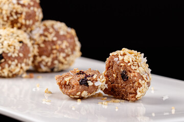 Beautiful candies with sesame seeds on a white plate on a black background