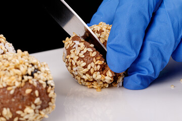 Beautiful candies with sesame seeds on a white plate on a black background