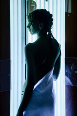 Portrait of cute elegant young woman enjoying tan in modern solarium