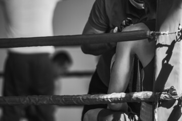The corner of the boxing ring. The boxer rests between rounds. Retro style black and white background image with shallow depth of field. Sharpness on the athlete in the corner of the ring.