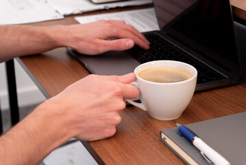 A cup of coffee whilst working at the office - Cup of coffee whilst person types