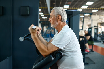 Elderly man, workout on exercise machine in gym