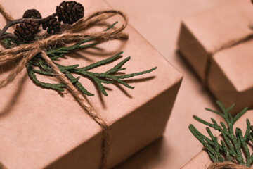 Festive decoration of gifts in eco-style.Gift boxes are wrapped in craft paper,tied with cotton thread,decorated with thuja leaves,cones and burlap,closeup.Christmas,New Year and eco-friendly concept.